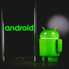 Zielony robot Android obok telefonu z napisem "android". Dowiedz się, jak sprawdzić, jaki Android masz w telefonie.