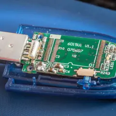 Rozłożony pendrive z widoczną zieloną płytką drukowaną i złączem USB. Płytka zawiera oznaczenia, np. "6015U1 V1.1". To wszystko, co potrzebne, by zrozumieć, **fat32 co to** jest za system plików.