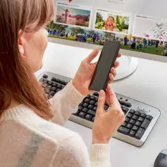 Kobieta trzyma smartfon, przygotowując podłączenie telefonu do monitora. Na ekranie widać zdjęcia z wydarzenia.