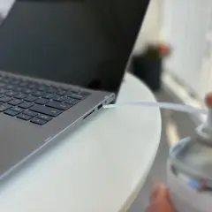 Czyszczenie laptopa z kurzu sprężonym powietrzem. Dmuchawa wylatuje z puszki w kierunku szczeliny obok klawiatury.