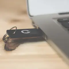 Pendrive z logo GitHub podłączony do laptopa. Dowiedz się, jak usunąć dane z komputera przed sprzedażą, by chronić swoją prywatność.
