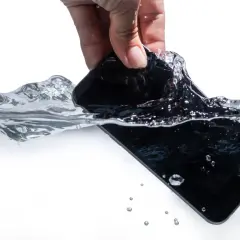 Dłoń wyciąga czarny telefon z wody. Zastanawiasz się, jak wysuszyć telefon po zalaniu?