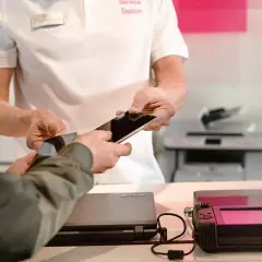 Pracownik serwisu pomaga w usuwaniu danych z telefonu, przekazując go klientowi.