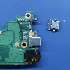 Luźne gniazdo USB C obok płyty głównej. Naprawa laptopa wymaga precyzji.