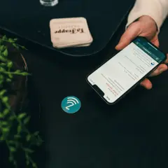 Dłoń trzyma smartfon z menu restauracji, obok symbol NFC. To pokazuje, jak działa NFC, co to jest i jak ułatwia płatności.