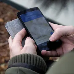 Osoba sprawdza na telefonie, jak zrobić wizytówkę w telefonie, korzystając z mapy.