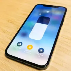 Na ekranie iPhone'a widać suwak jasności i opcje: Tryb ciemny, Night Shift i True Tone. Dowiedz się, jak zmienic kolor godziny w iPhone.