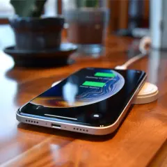 Smartfon ładuje się bezprzewodowo na podstawce. To jeden ze sposobów, jak szybko naładować telefon, gdy potrzebujesz energii.