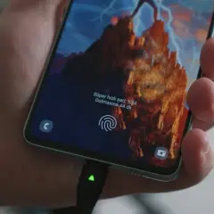 Dłoń trzyma smartfon z włączonym szybkim ładowaniem. Na ekranie widać informację o naładowaniu do 74% i szacowany czas do pełnego naładowania.