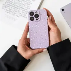 Ręce trzymają fioletowe etui na telefon w kwiatki. Dowiedz się, jak wyczyścić matowe etui, aby wyglądało jak nowe.