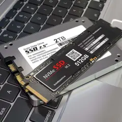 Dwa dyski SSD: 2,5-calowy NGFF i mniejszy NVMe M.2, leżące na klawiaturze laptopa.