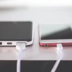 Dwa telefony podłączone do ładowania. Jeden z nich ma zepsute gniazdo ładowania w telefonie, co uniemożliwia mu pobieranie energii.