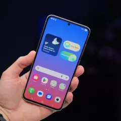 Dłoń trzyma telefon Samsung z widocznymi ikonami aplikacji i widżetem pogody. Ustawienia telefonu Samsung są łatwo dostępne.