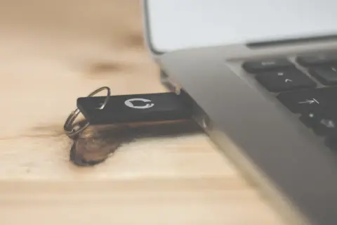 Pendrive z logo GitHub podłączony do laptopa. Dowiedz się, jak usunąć dane z komputera przed sprzedażą, by chronić swoją prywatność.