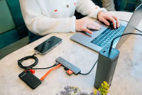 Przenośny dysk i telefon podłączone do laptopa przez hub, wykorzystując pełną **usb 3.2 speed** do szybkiego transferu danych.