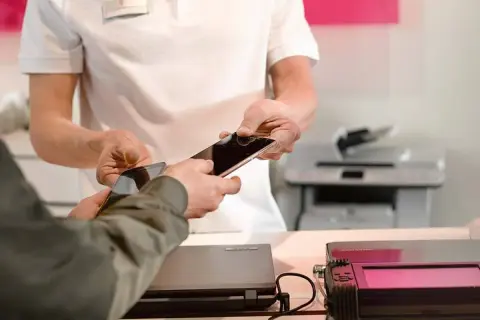 Pracownik serwisu pomaga w usuwaniu danych z telefonu, przekazując go klientowi.