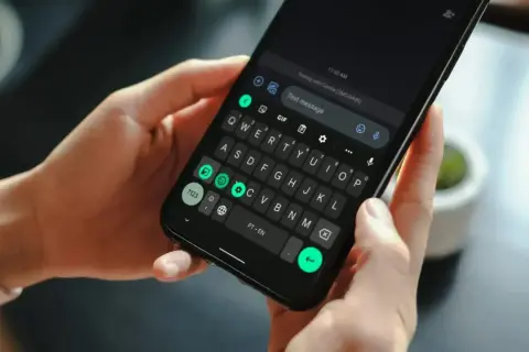 Dłonie trzymają smartfon z klawiaturą. Wpisuję wiadomość, odkrywając historię schowka.