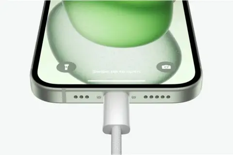 iPhone z zieloną tapetą, podłączony do ładowania. Możliwość powershare iPhone.