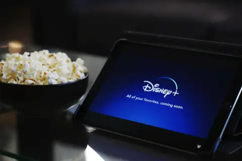 Tablet z logo Disney+ i miska popcornu. Idealne do wspólnego oglądania, nawet przy **disney+ dzielenie konta**.