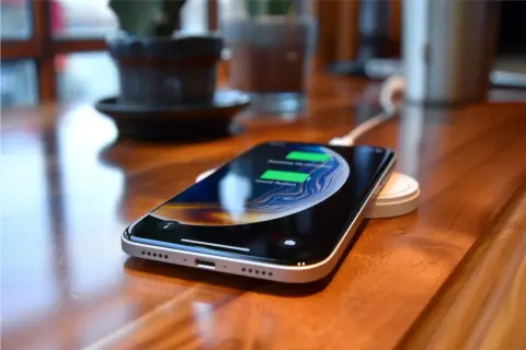 Smartfon ładuje się bezprzewodowo na podstawce. To jeden ze sposobów, jak szybko naładować telefon, gdy potrzebujesz energii.