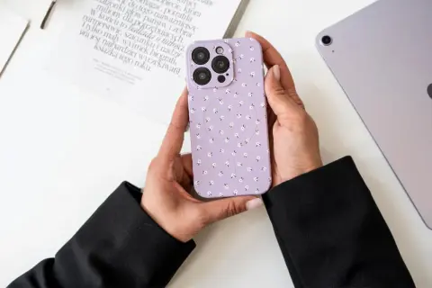Ręce trzymają fioletowe etui na telefon w kwiatki. Dowiedz się, jak wyczyścić matowe etui, aby wyglądało jak nowe.