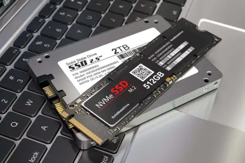 Dwa dyski SSD: 2,5-calowy NGFF i mniejszy NVMe M.2, leżące na klawiaturze laptopa.