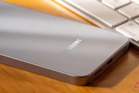 Srebrny telefon Samsung leży obok klawiatury. Jego bateria adaptacyjna zapewnia długie działanie.