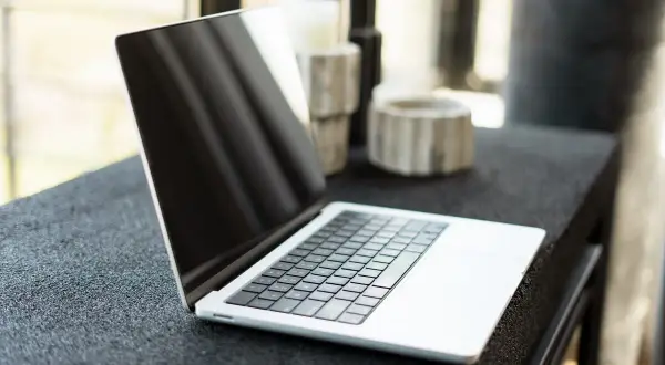 Nowy laptop czeka na pierwsze uruchomienie komputera. Na blacie obok ozdobne wazony.