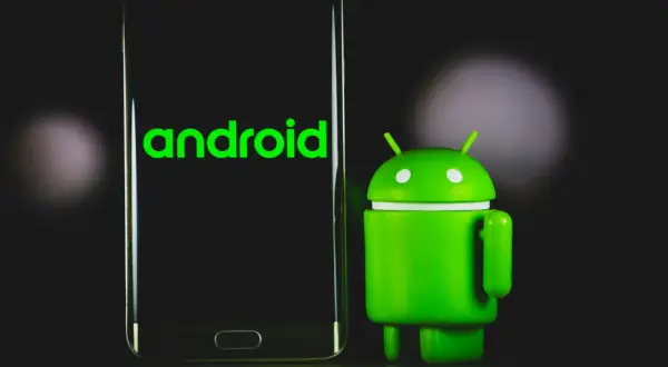 Zielony robot Android obok telefonu z napisem "android". Dowiedz się, jak sprawdzić, jaki Android masz w telefonie.