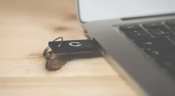 Pendrive z logo GitHub podłączony do laptopa. Dowiedz się, jak usunąć dane z komputera przed sprzedażą, by chronić swoją prywatność.