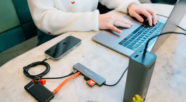 Przenośny dysk i telefon podłączone do laptopa przez hub, wykorzystując pełną **usb 3.2 speed** do szybkiego transferu danych.