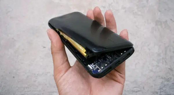 Uszkodzony powerbank z widoczną baterią i płytką drukowaną. Czy to problem z gwarancją na baterie w telefonie?