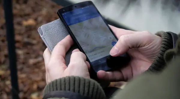 Osoba sprawdza na telefonie, jak zrobić wizytówkę w telefonie, korzystając z mapy.