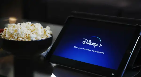 Tablet z logo Disney+ i miska popcornu. Idealne do wspólnego oglądania, nawet przy **disney+ dzielenie konta**.