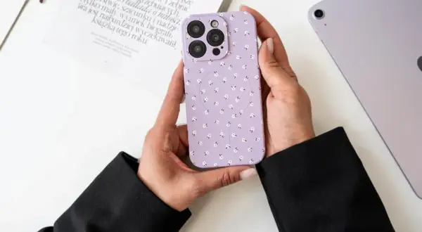 Ręce trzymają fioletowe etui na telefon w kwiatki. Dowiedz się, jak wyczyścić matowe etui, aby wyglądało jak nowe.