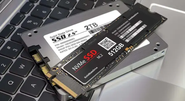 Dwa dyski SSD: 2,5-calowy NGFF i mniejszy NVMe M.2, leżące na klawiaturze laptopa.