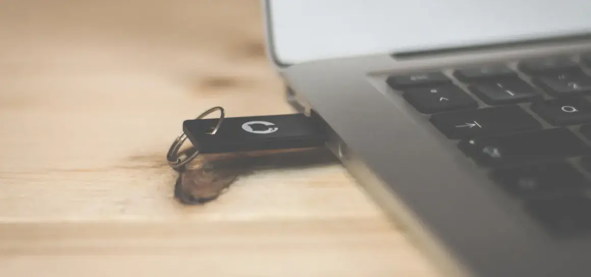 Pendrive z logo GitHub podłączony do laptopa. Dowiedz się, jak usunąć dane z komputera przed sprzedażą, by chronić swoją prywatność.