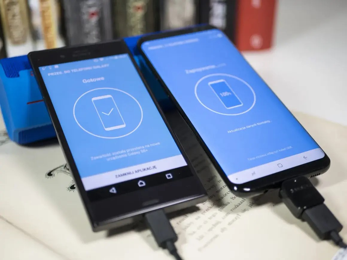 Dwa telefony połączone kablem USB. Jeden z nich pokazuje komunikat "Gotowe", drugi "100% Aktualizacja danych Kontakty...", co jest częścią procesu jak uruchomić nowy telefon Samsung.