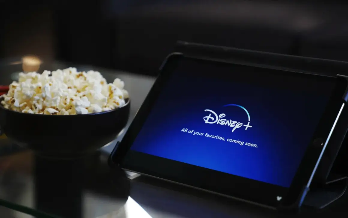 Tablet z logo Disney+ i miska popcornu. Idealne do wspólnego oglądania, nawet przy **disney+ dzielenie konta**.