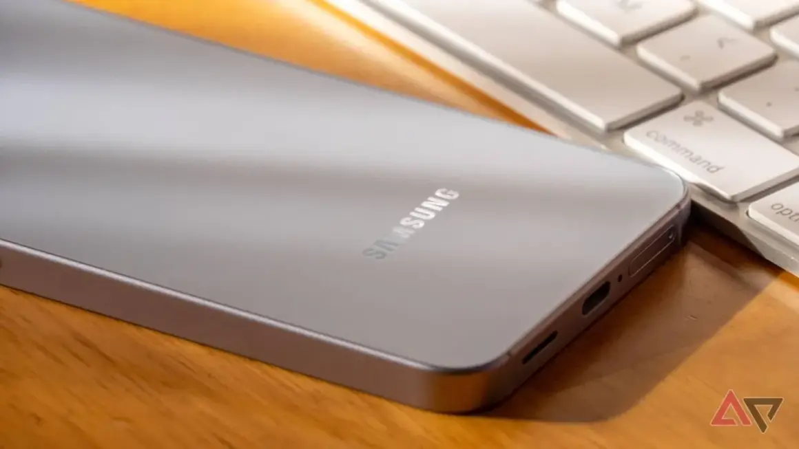 Srebrny telefon Samsung leży obok klawiatury. Jego bateria adaptacyjna zapewnia długie działanie.