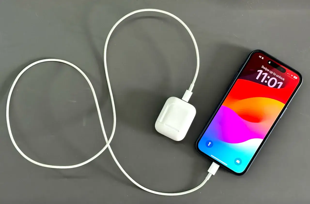 iPhone w trakcie ładowania. Biały kabel łączy telefon z ładowarką.