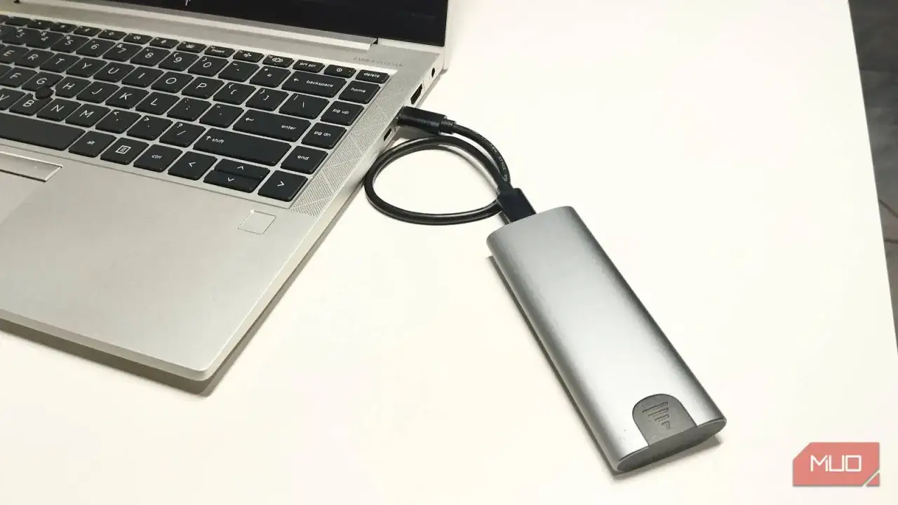 Jak podłączyć dysk SSD do laptopa przez USB? Srebrna obudowa dysku zewnętrznego połączona kablem z portem USB laptopa.
