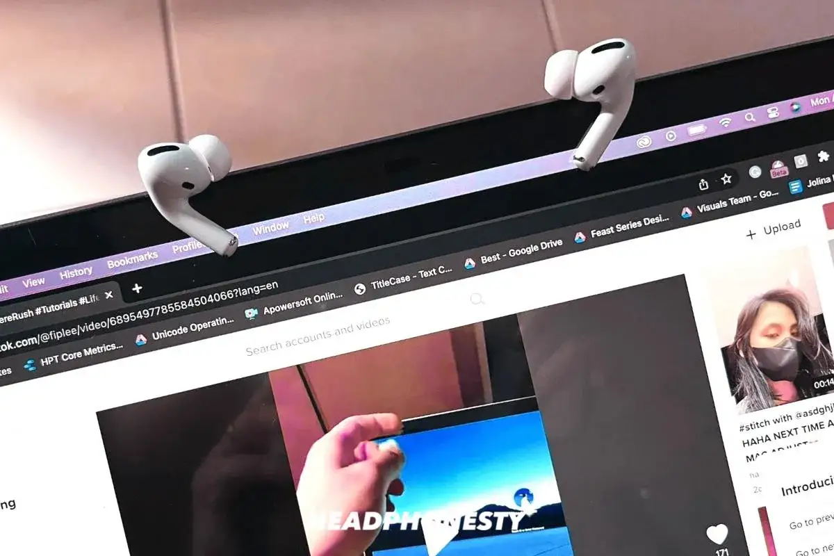 Dwa białe słuchawki AirPods leżą na krawędzi ekranu laptopa, sugerując, jak ładować AirPods bez etui, gdy szukasz poradnik&oacute;w online.