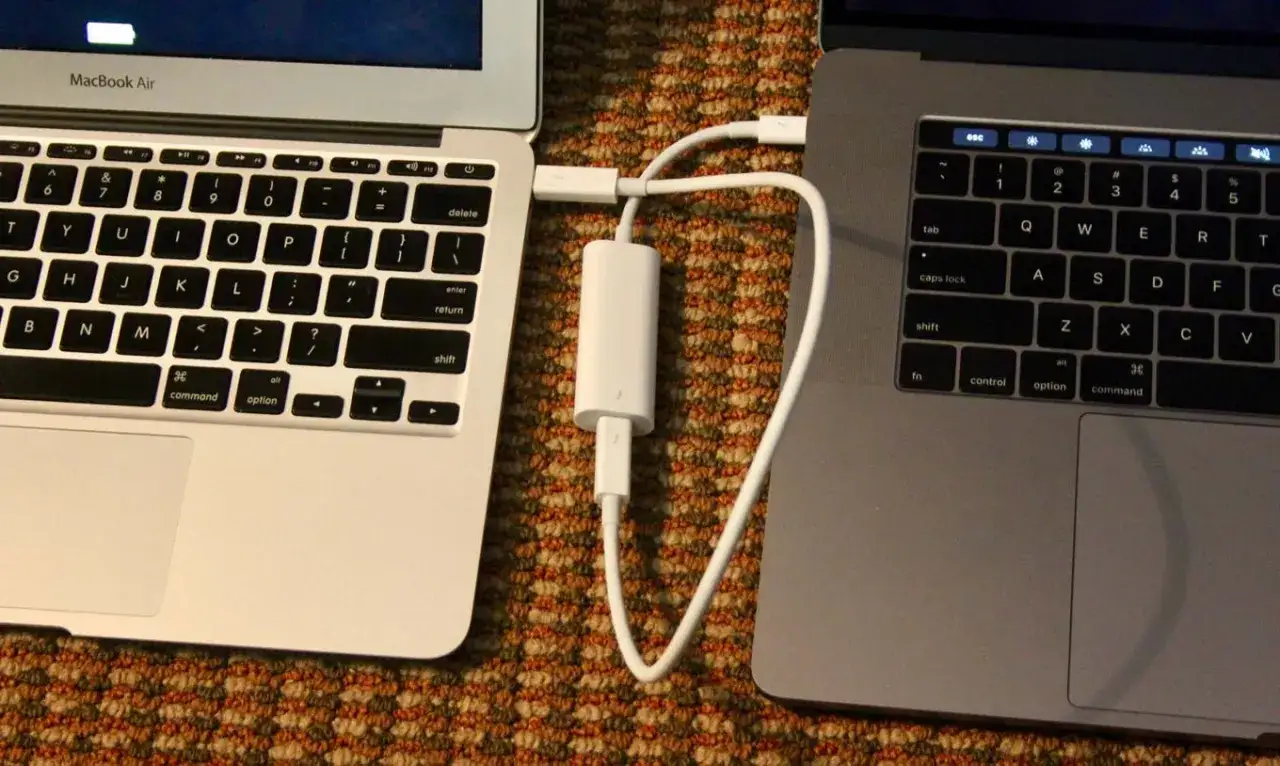Dwa laptopy MacBook połączone kablem Thunderbolt. Tak przenieść dane z Maca na Maca.