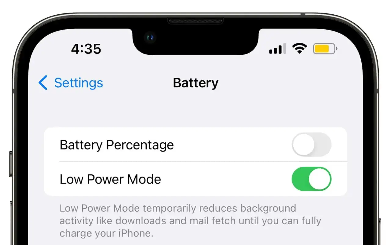 Na ekranie iPhone'a włączony tryb oszczędzania energii. Ikona baterii jest żółta.