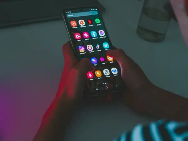 Dłonie trzymają smartfon z ikonami aplikacji, w tym Instagram i TikTok. Wskazówka do oszczędzania baterii: wyłącz niepotrzebne aplikacje.