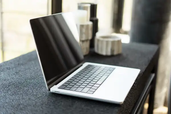 Nowy laptop czeka na pierwsze uruchomienie komputera. Na blacie obok ozdobne wazony.