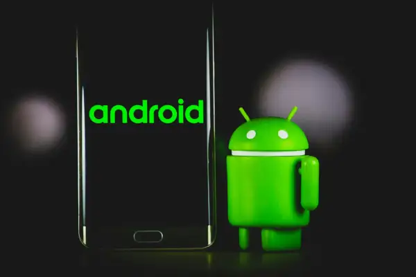 Zielony robot Android obok telefonu z napisem "android". Dowiedz się, jak sprawdzić, jaki Android masz w telefonie.