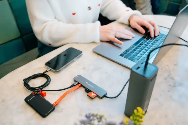 Przenośny dysk i telefon podłączone do laptopa przez hub, wykorzystując pełną **usb 3.2 speed** do szybkiego transferu danych.