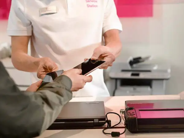 Pracownik serwisu pomaga w usuwaniu danych z telefonu, przekazując go klientowi.